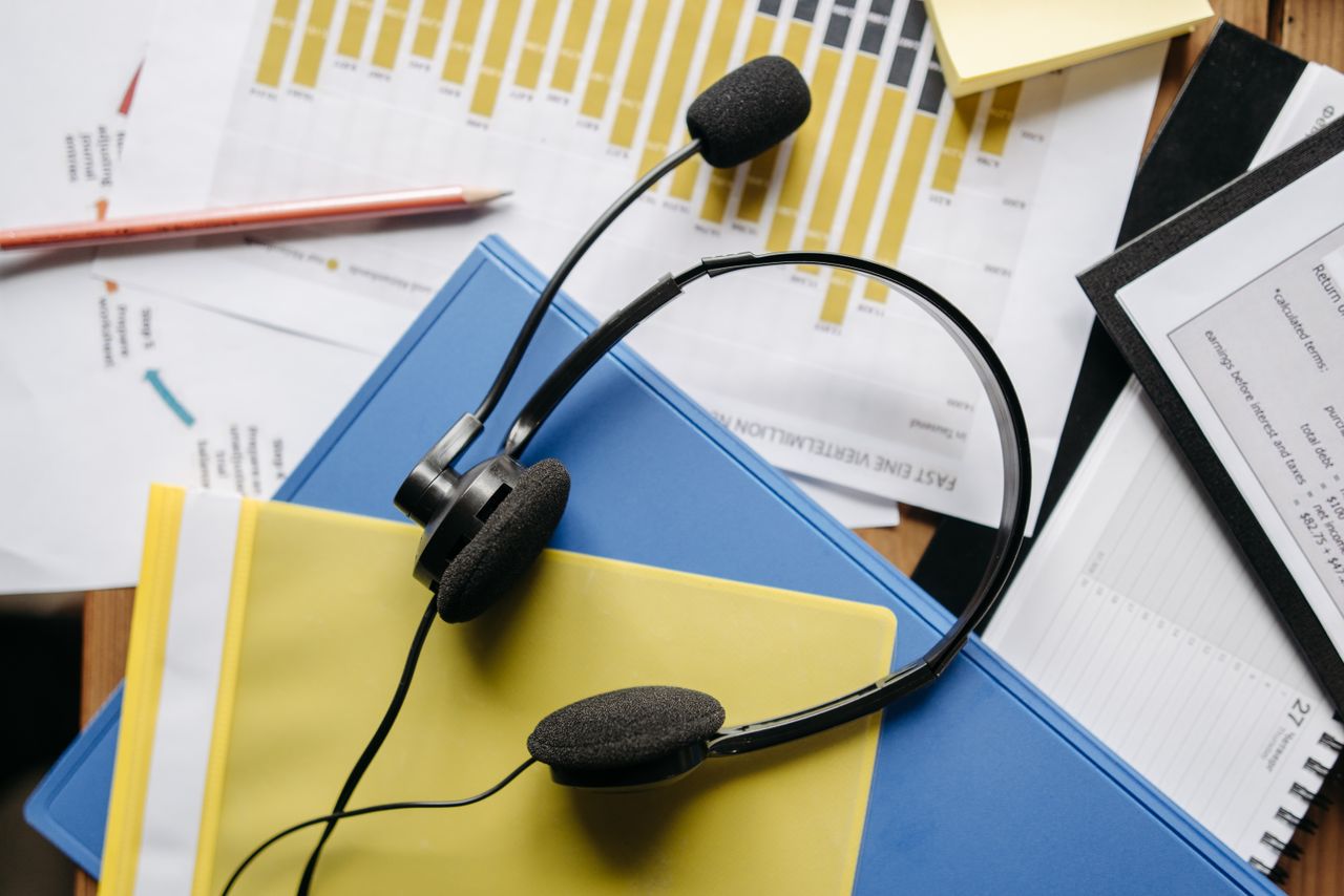 Home Close-up of an office desk with headset, charts, and documents showcasing customer service support.