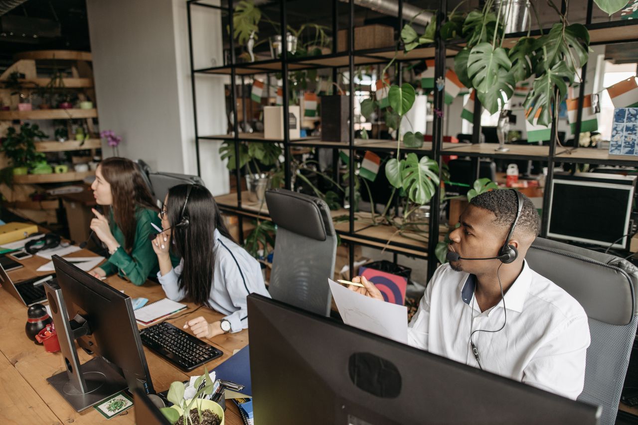 Home A diverse team collaborates in a modern office with plants and technology.